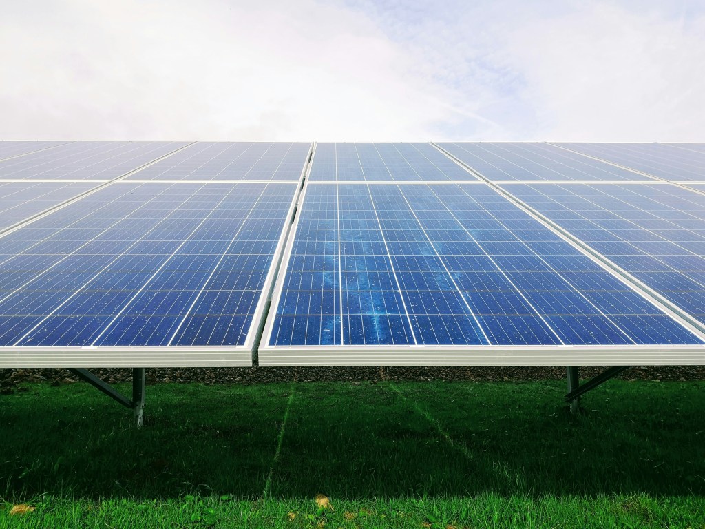 Close-up of solar panel installation on green grass under a blue sky in Michigan, showcasing renewable energy technology.