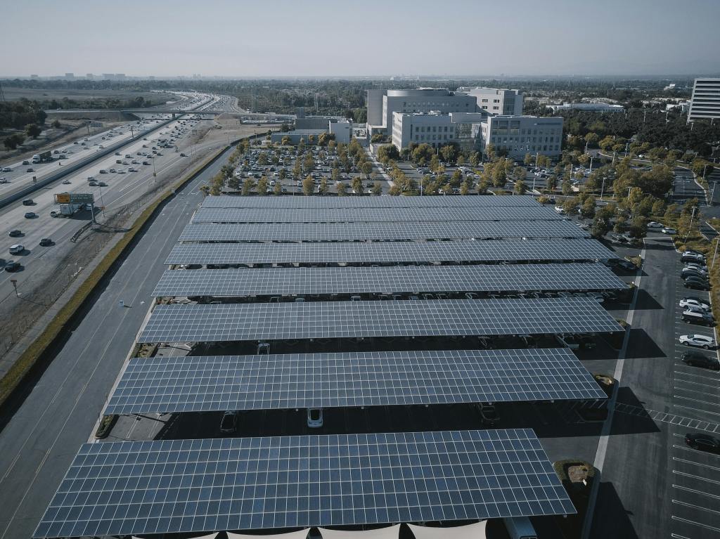 Solar panel-covered parking lot near a busy highway and commercial buildings, showcasing sustainable energy use in Michigan’s urban areas.